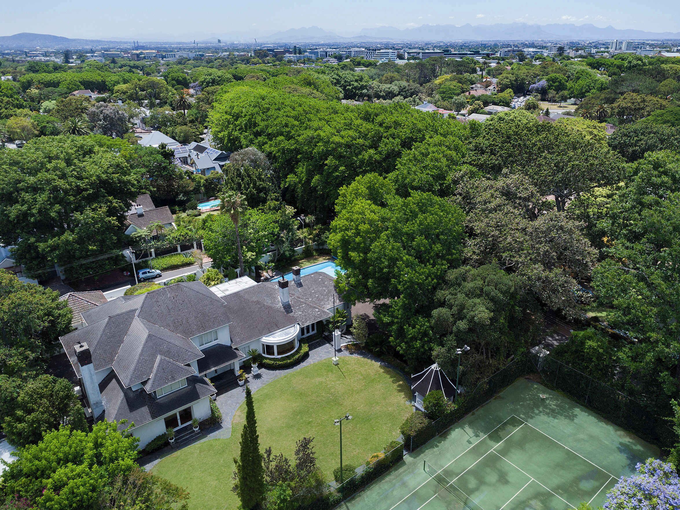 A residential area with houses, a tennis court, and lush greenery.