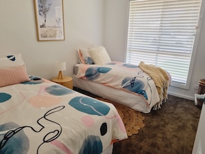 A bedroom with two beds, a window with blinds, a lamp, and a framed picture on the wall. - SurfMist House - WiFi (Robe)