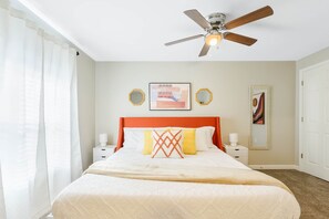 A bedroom with a bed, a ceiling fan, two bedside tables, and a nightstand.