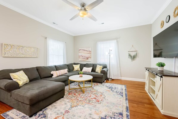 A modern living room with a sectional sofa, a round coffee table, and a decorative rug.
