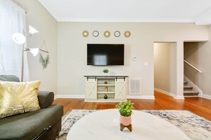A living room with a sofa, coffee table, TV, and decorative wall pieces.