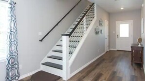A staircase with a handrail, a patterned curtain, and a wooden floor.
