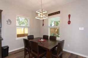 A dining area with a wooden table and chairs, a hanging light fixture, and a wall sign. - Lake Ridge Oasis (Belton)