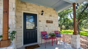 A front porch with a black door, two red chairs with 'I Love House' signs, and a 'Lake' sign on the wall.