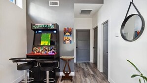 A hallway with a retro arcade machine, a small table, and a mirror on the wall. - The Gregory: 2 Bed/1 Bath Guesthouse (Phoenix)