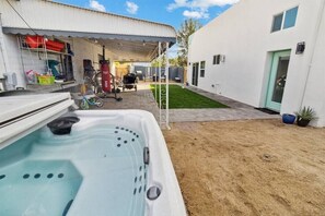 Una casa moderna con jacuzzi en el patio trasero, garaje techado y césped bien cuidado.