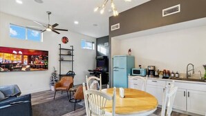 A modern kitchen with white cabinets, a blue refrigerator, and a dining area with a wooden table and white chairs. - The Gregory: 2 Bed/1 Bath Guesthouse (Phoenix)