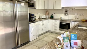 A modern kitchen with stainless steel appliances, white cabinetry, a built-in oven, and a granite countertop. - theGREEN Villa, your solar powered home away from home (Cape Town)