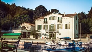 A waterfront property with a large building featuring balconies and a stone archway. - Villa del Mar - LUXURY VILLA with POOL & GARDEN (Rogac, Solta)