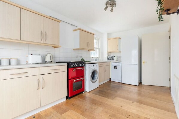 Enjoy cooking in this well-equipped kitchen with a washing machine, refrigerator, and oven.