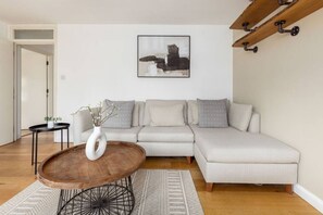 Relax in a stylish living room with a light-colored sofa, round coffee table, and abstract art.