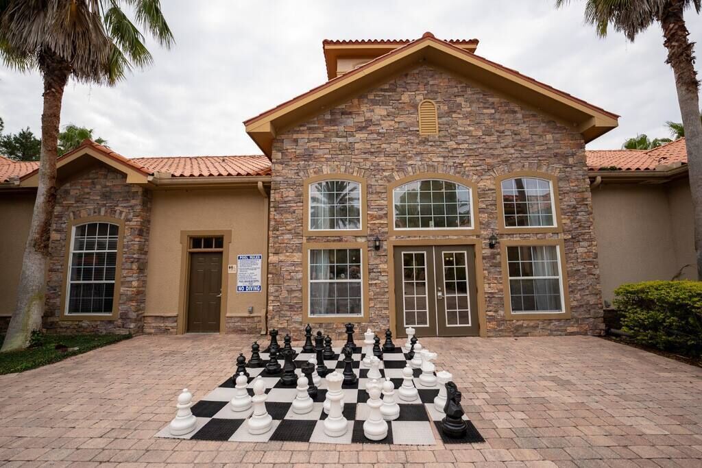 A stone building with a large chessboard in front.