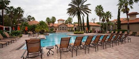 A pool area with lounge chairs and palm trees.
