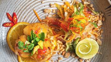 Un plato de comida con diversas verduras, nueces y un gajo de lima.