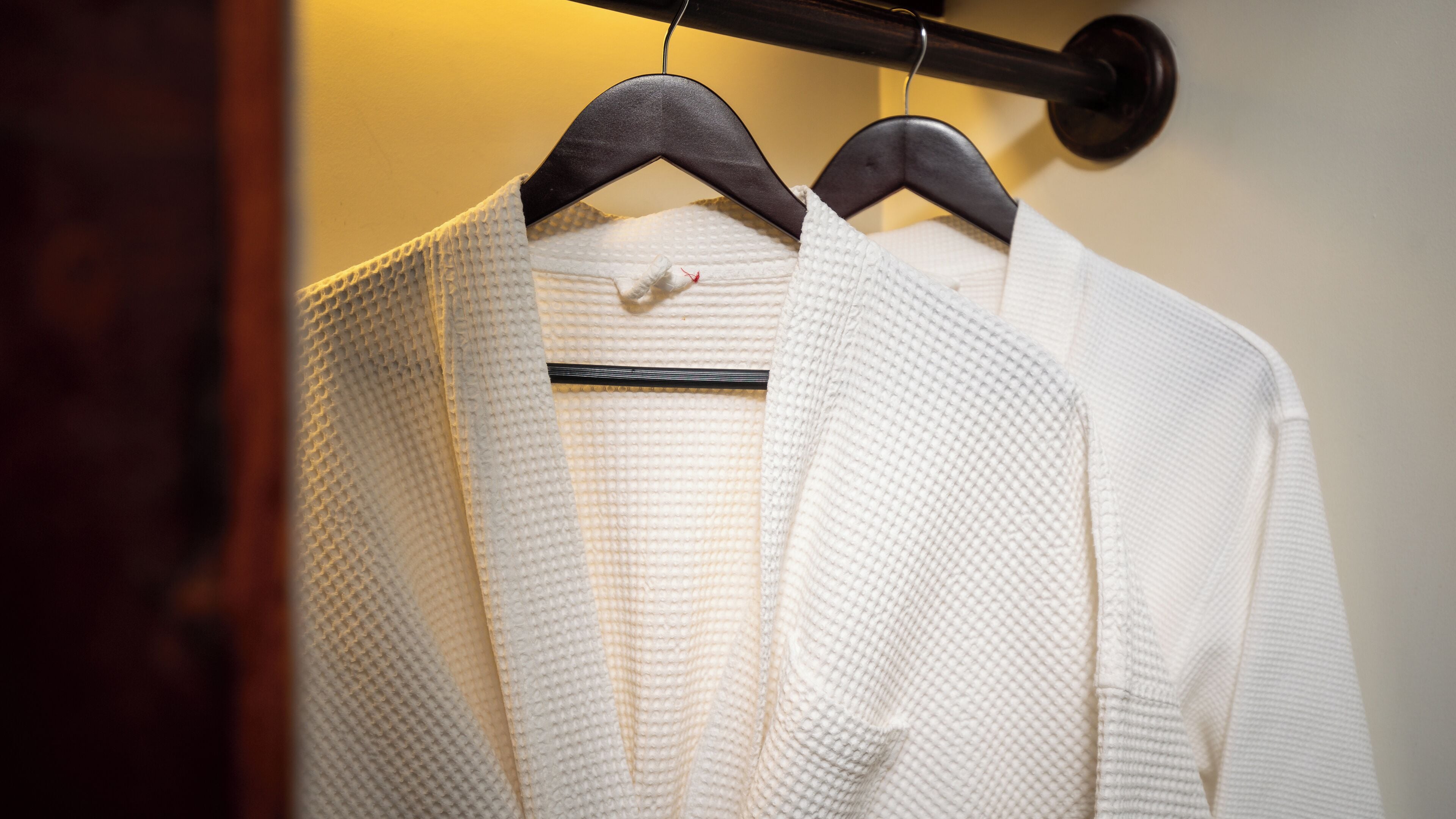 A white robe hanging on a wooden hanger.
