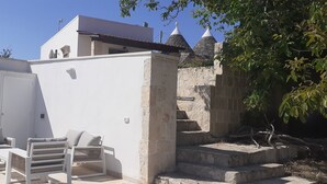 A white building with a flat roof and a stone staircase leading to a higher level. - Trullo Genista with Private Pool in the Golden Triangle, Puglia Italy (Martina Franca)