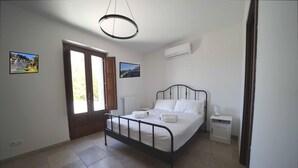 A bedroom with a bed, bedside table, and a window. - Trullo Genista with Private Pool in the Golden Triangle, Puglia Italy (Martina Franca)