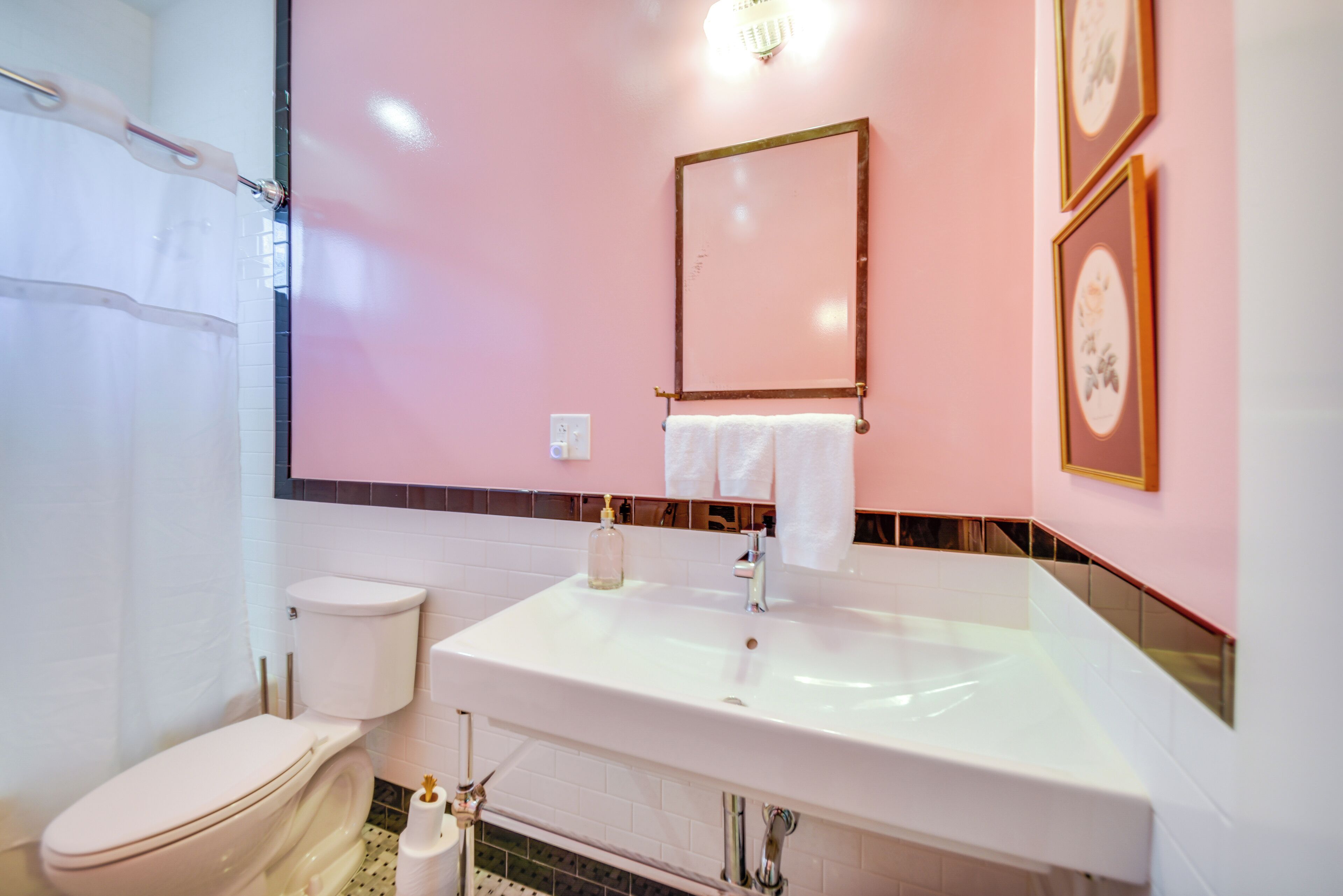 Un baño con inodoro y lavamanos blancos, y un espejo sobre el lavamanos.