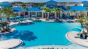 Une grande piscine extérieure dotée de plusieurs espaces de détente et bordée de palmiers.