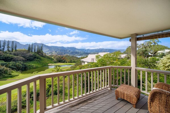 Un balcon avec vue sur un terrain de golf, des montagnes et un lac.