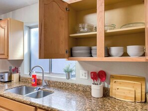 Eine Küche mit Granit-Arbeitsplatten, einer doppelten Spüle, Holzschränken und einem Fenster.