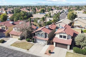 A residential area with houses featuring red-tiled roofs, some with solar panels, surrounded by greenery and palm trees. - Chandler 3BR | Pool + Game Room | Pet Friendly (Chandler)