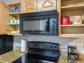 A kitchen with a black microwave, a stove, and a coffee maker. - Chandler 3BR | Pool + Game Room | Pet Friendly (Chandler)