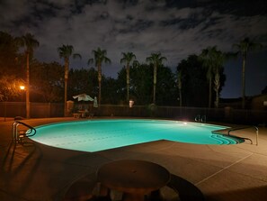 Ein Pool mit Fliesen umgeben von Palmen und einem Zaun.