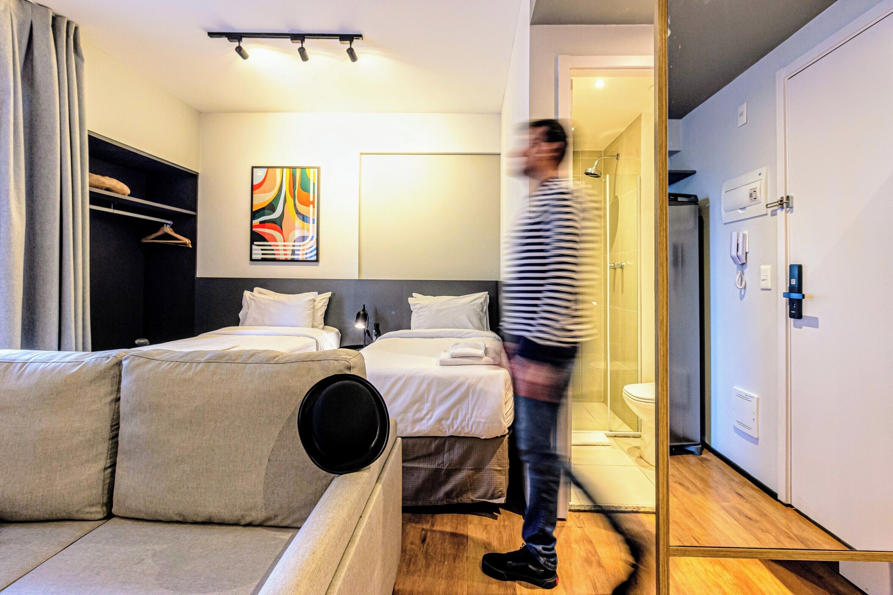 A modern hotel room with a sofa, a bed, a bathroom, and a walk-in closet.