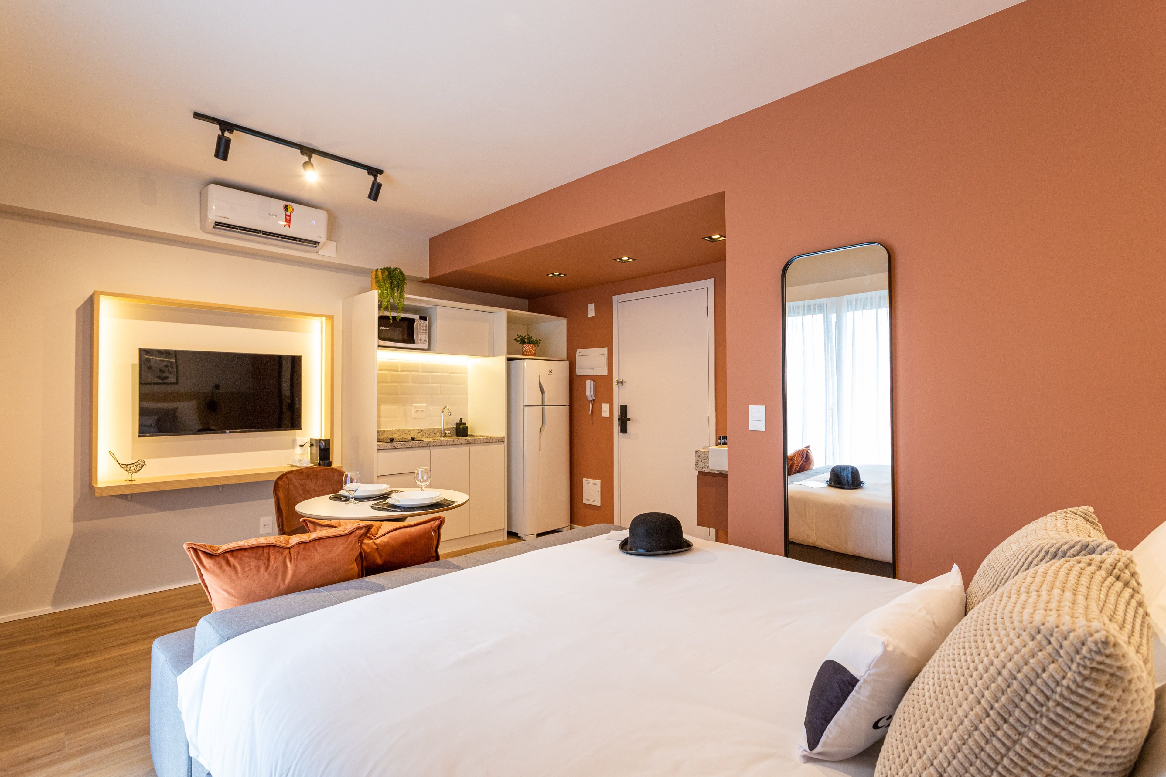 A hotel room with a large bed, a dining area, and a kitchenette.
