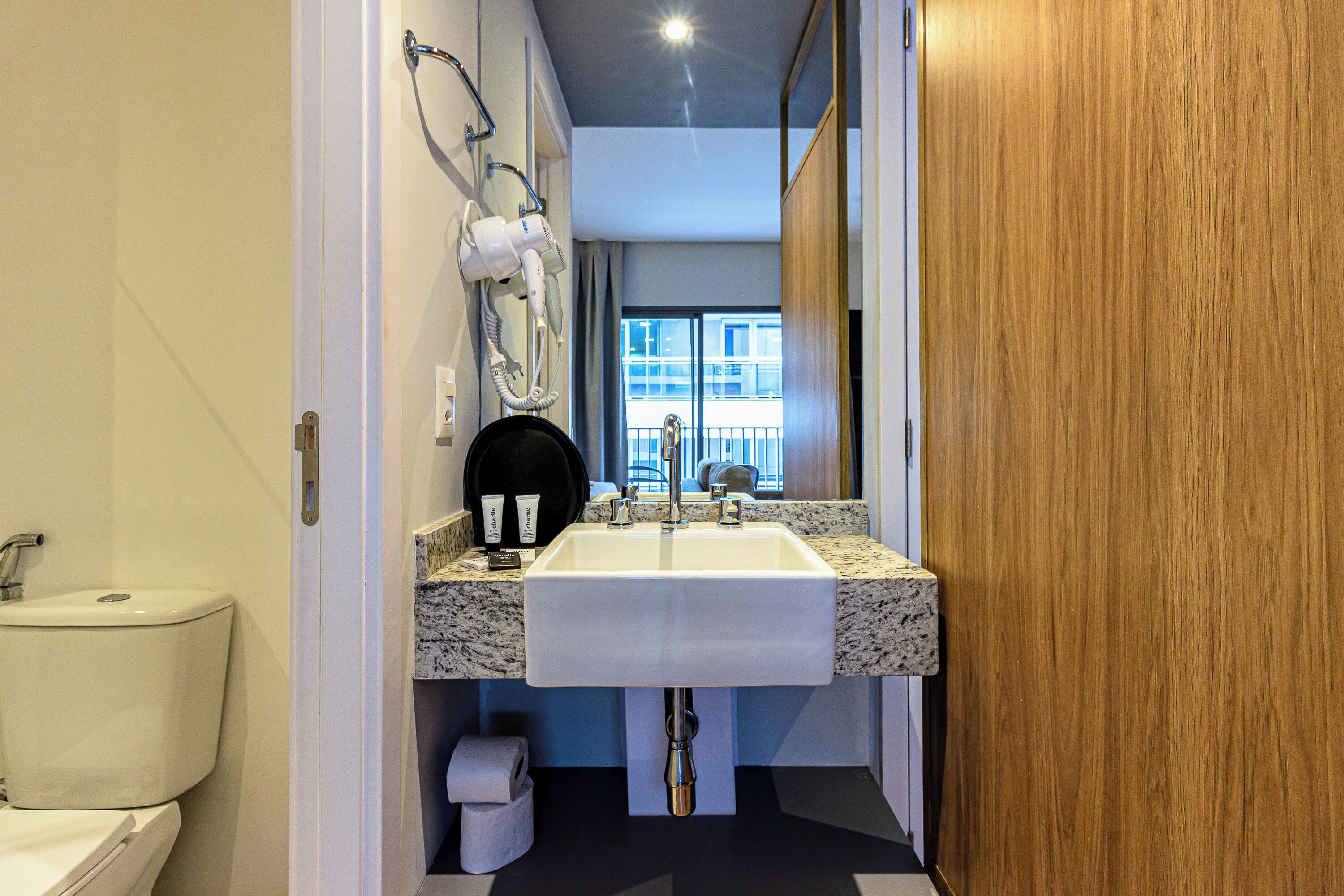 A bathroom with a white sink, a mirror, and a hairdryer mounted on the wall.