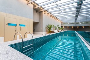 An indoor swimming pool with clear water, a tiled floor, and a glass ceiling. - Charlie Aeroporto Congonhas CGH (São Paulo)