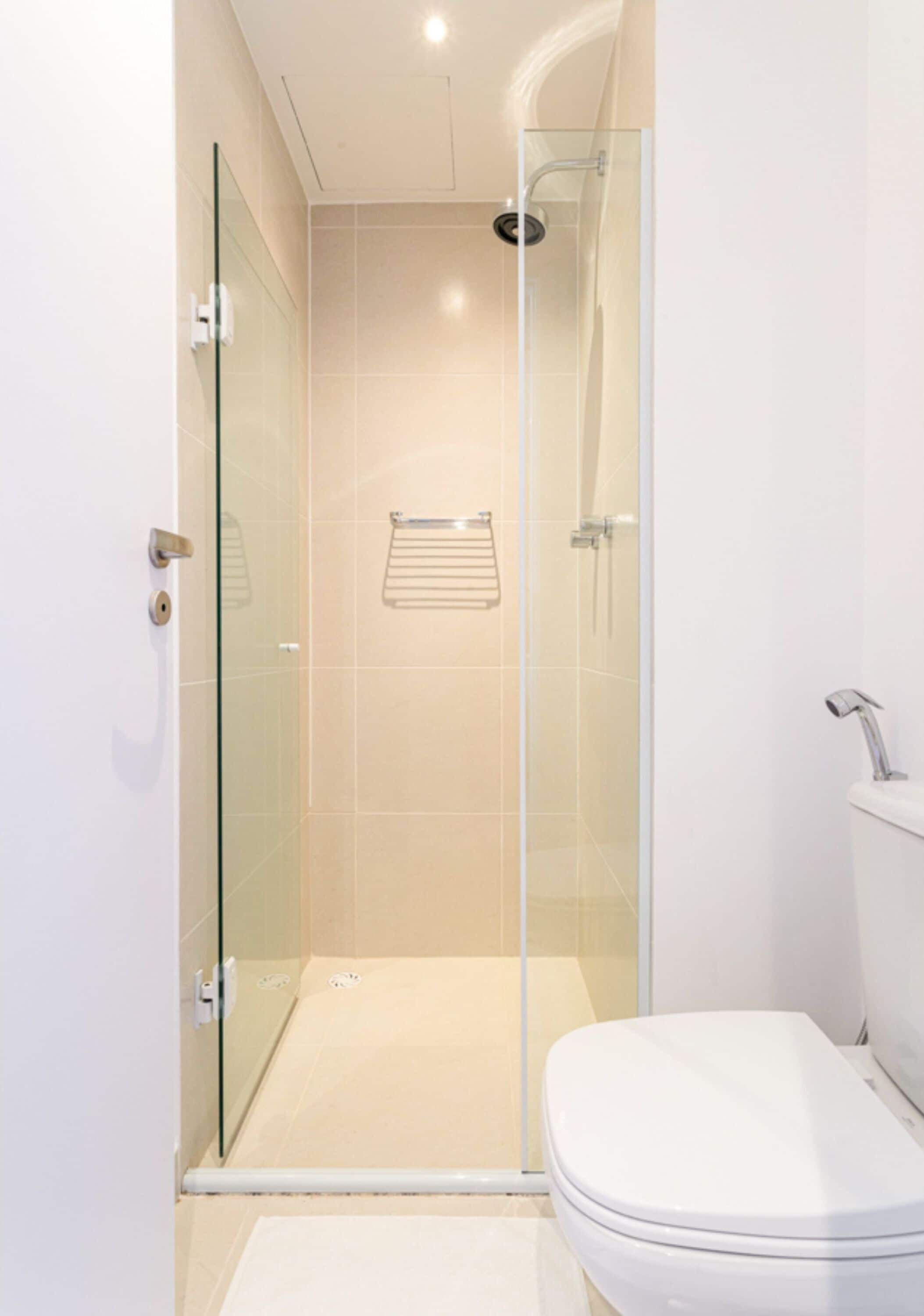 Ein modernes Badezimmer mit einer gläsernen Duschkabine, einer weißen Toilette und einem Handtuchhalter.