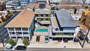 Un edificio a più piani con piscina, parcheggio e una strada ben visibile.
