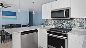 Una cucina moderna con mobili bianchi, un forno a microonde in acciaio inox, forno integrato e lavastoviglie.