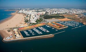An aerial view of a coastal city with a marina, beach, and residential buildings. - Redmayne Apartment, Portimão, Algarve (Portimão)