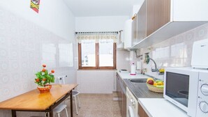 Una cocina compacta con una mesa de madera, dos sillas, una lavadora y un microondas.