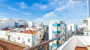 Un paisaje urbano con edificios, cielo despejado y un balc ón con barandilla.