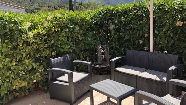 An outdoor patio with wicker furniture, including a sofa and chairs, and a small table. - Charming air-conditioned house in Sorède sleeps 4/6, 6 km from Argelès Sur Mer. (Sorède)