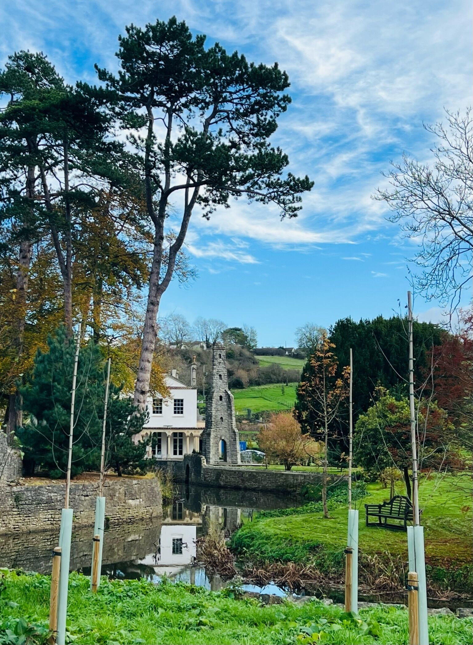 A historic stone building with a tower, surrounded by lush greenery and a clear sky.