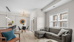 A modern living room with a sectional sofa, a coffee table, and a dining area with a round table and chairs.