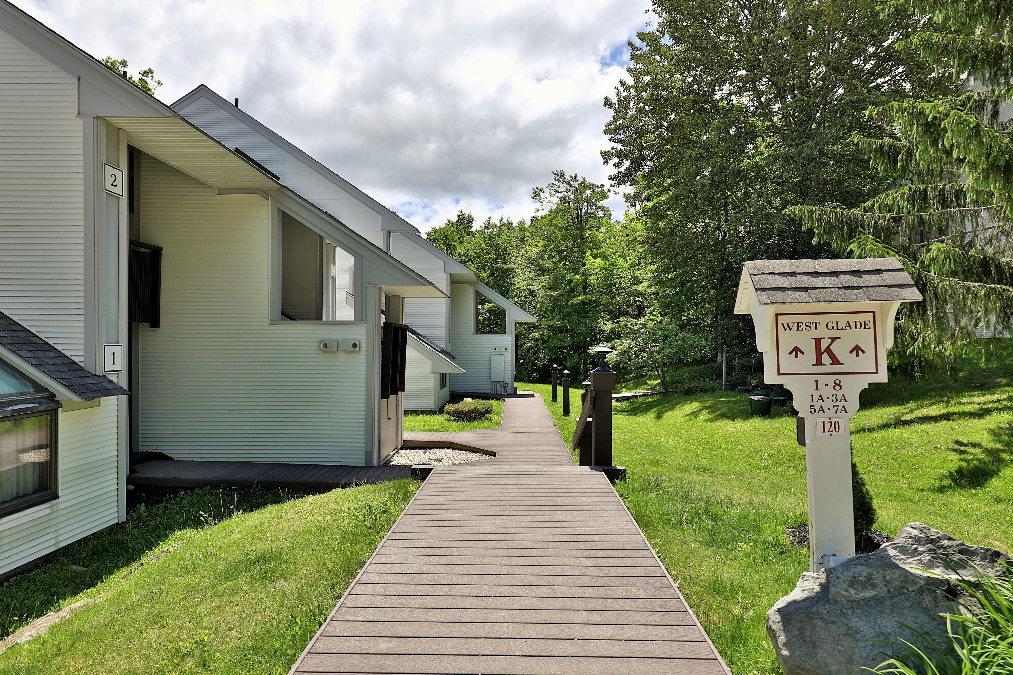 A pathway leading to a row of mobile homes with a sign indicating 'West Glade' and directional arrows.