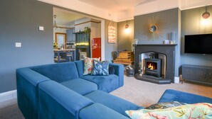 A living room with a blue sectional sofa, a fireplace, and a television. - Waverley (Lyme Regis)