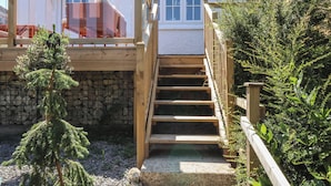 A wooden staircase leading to a deck with a stone wall and a small tree. - Waverley (Lyme Regis)