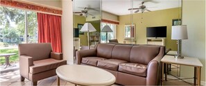 Relax in comfort with a sofa and armchair facing a large window offering a view of the outdoors.