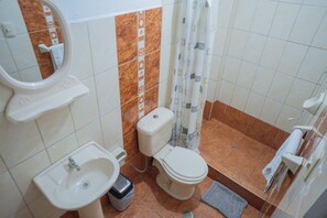 Casa de banho com lavatório, sanita e cortina de chuveiro.