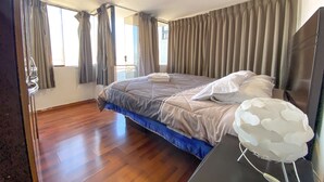 A hotel room with a large bed, wooden flooring, a bedside table with a lamp, and a view of the outdoors through the window. - PRIVATE APART WITH AMAZING VIEW OF CUSCO (Cusco)