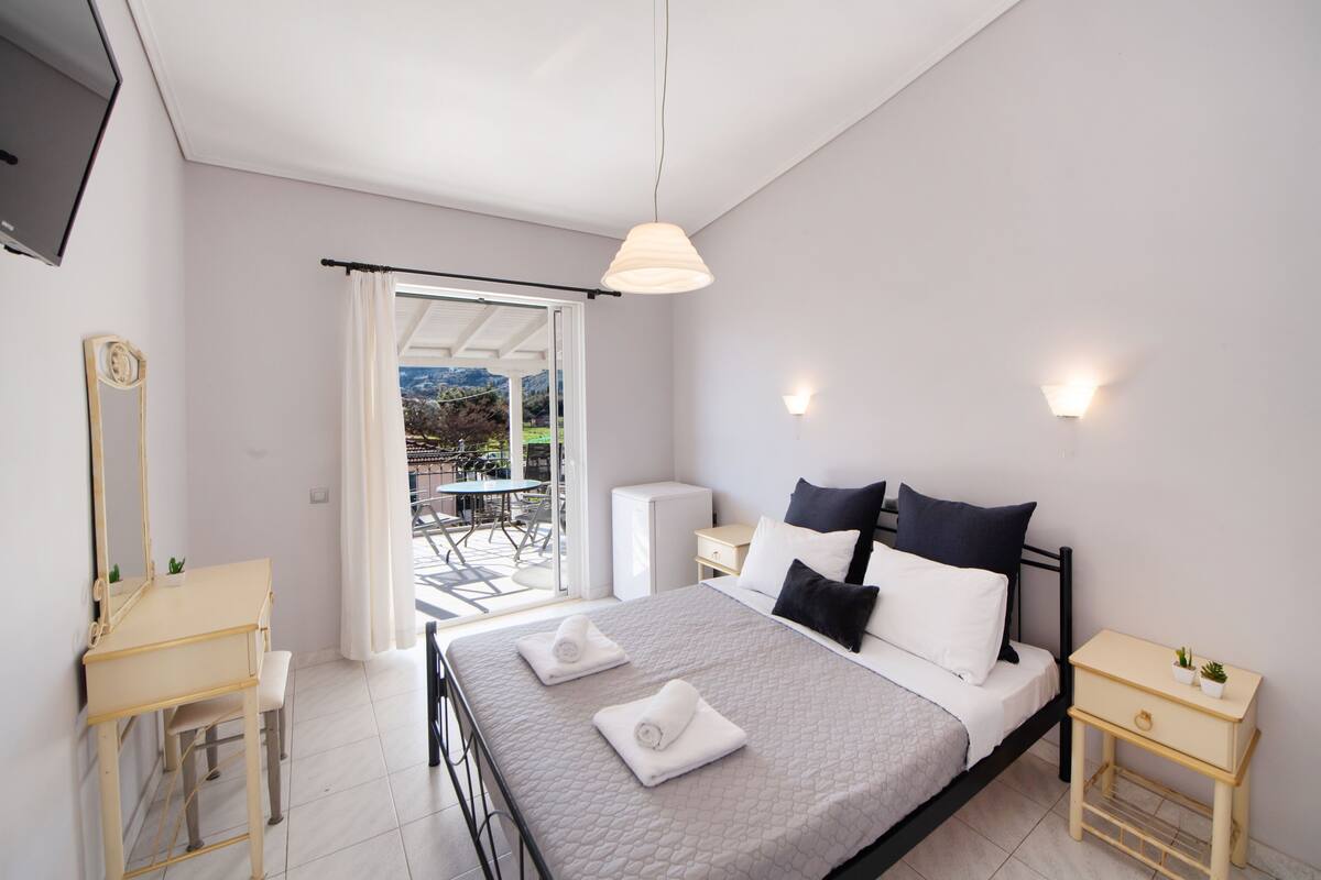 Un dormitorio con cama, mesitas de noche, un espejo y vistas al exterior.