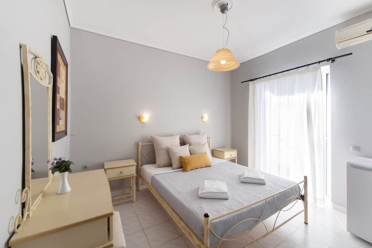 Un dormitorio moderno con cama, mesitas de noche, cómoda, espejo y lámpara colgante.