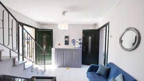 A modern living room with a blue sofa, a glass coffee table, and a staircase with metal railings. - George House (Lefkada)
